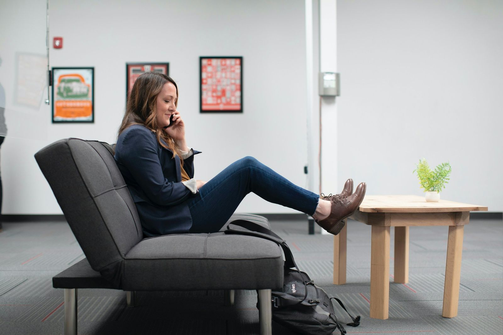 A saleswoman on a phone call, relaxed on a sofa in a modern office